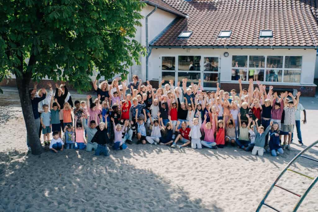 Mühlenbergschule Osloß Grundschule, fröhliche Kinder im Schulhof bei Sonnenschein.